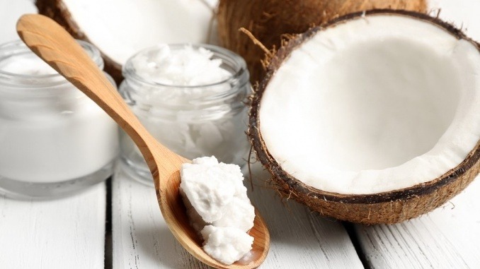 Coconut with jars of coconut oil and cosmetic cream on wooden ba